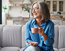 Senior woman sitting on couch with coffee cup
