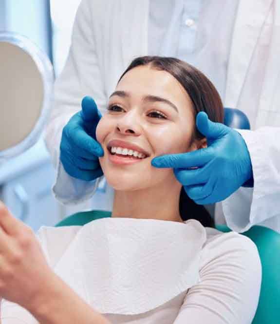 a patient checking her teeth with a mirror